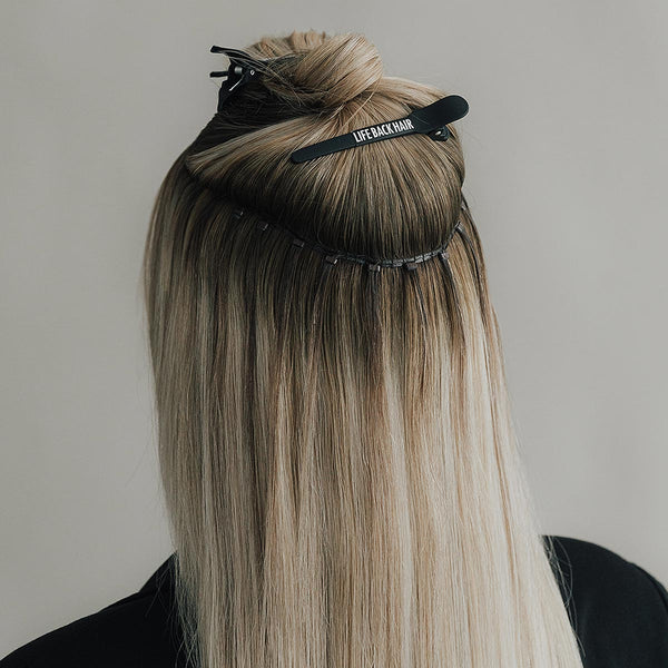 Nahaufnahme einer Weft-Extension-Anwendung mit LIFEBACKHAIR Markenwerkzeug am Hinterkopf