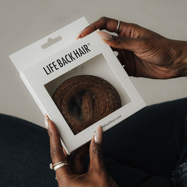 Person hält eine LIFEBACKHAIR Lace-Closure-Verpackung in Braun in den Händen