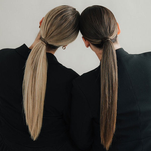 Zwei Frauen von hinten mit langen, glatten Pferdeschwänzen in Blond und Braun