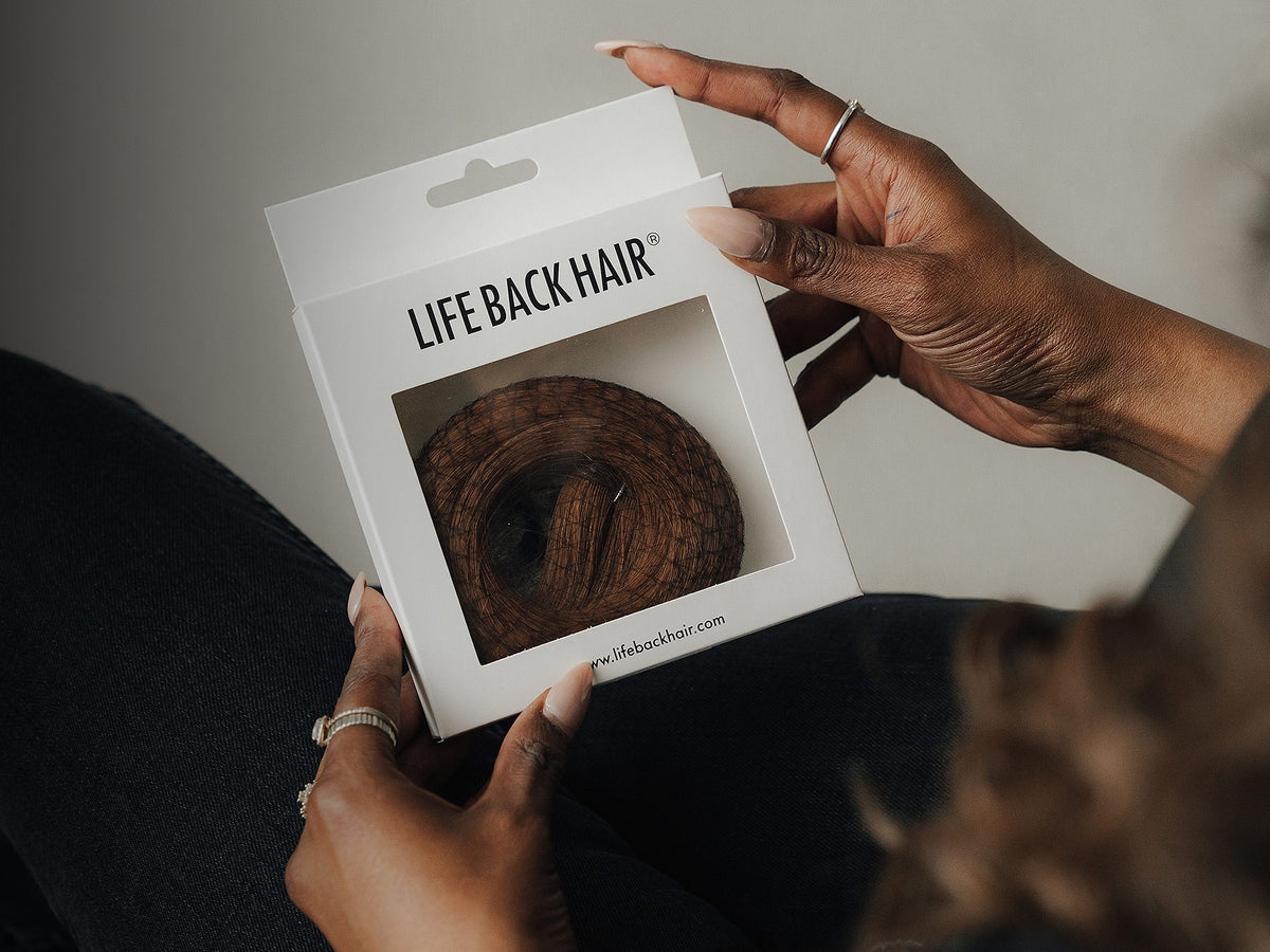 Hände halten eine LIFEBACKHAIR®-Verpackung mit sichtbarer Echthaar-Extension